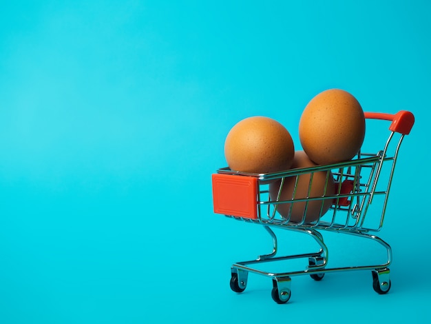 Eieren in een kleine trolley op een blauwe achtergrond