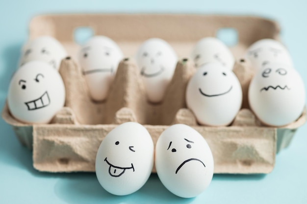 Eieren met grappige en droevige gezichten op blauwe achtergrond
