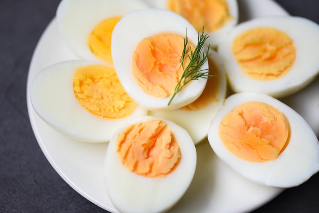 Eieren ontbijt, verse eieren menu eten gekookte eieren in een witte plaat versierd met bladeren groene dille achtergrond, in tweeën gesneden eierdooiers voor het koken van gezond eten