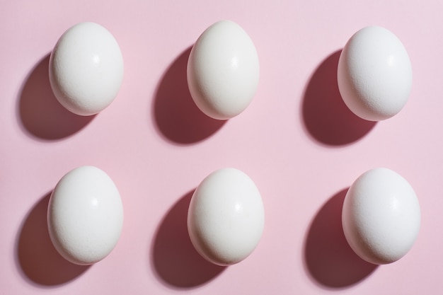 Eieren tafel. Zes witte eieren op een roze papier achtergrond. Bovenaanzicht, plat lag.