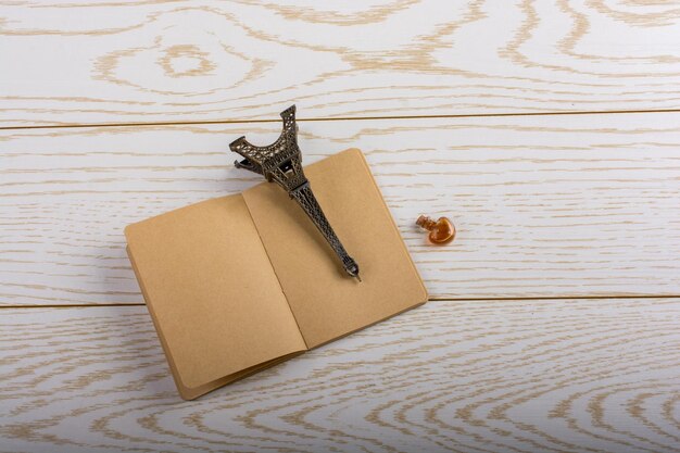 Eiffel tower miniature and a potion bottle on a brown notebook on wooden background