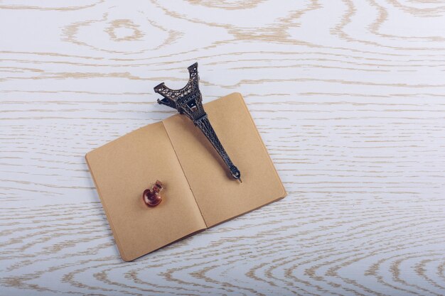 Eiffel tower miniature and a potion bottle on a brown notebook on a wooden background