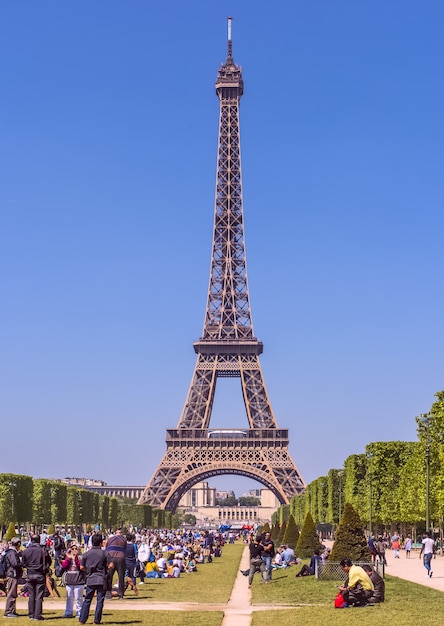 eiffel tower on a sunny clear day a mars field filled with people in the foreground paris france