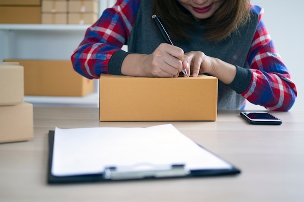 Eigenaren van kleine bedrijven schrijven namen om zich voor te bereiden op het bezorgen van pakketten aan klanten. Kleine bedrijven die online verkopen en online producten bestellen