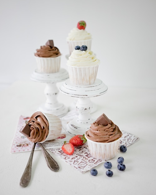 Eigengemaakte cupcakes met chocolade en vanilleroom op houten caketribunes op witte achtergrond