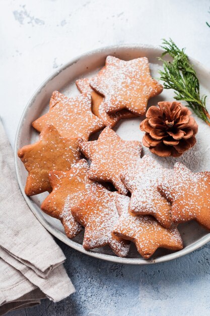 Eigengemaakte de peperkoekkoekjes van de Kerstmisstervorm in ceramische plaat op oude concrete grijze oppervlakte. Bovenaanzicht