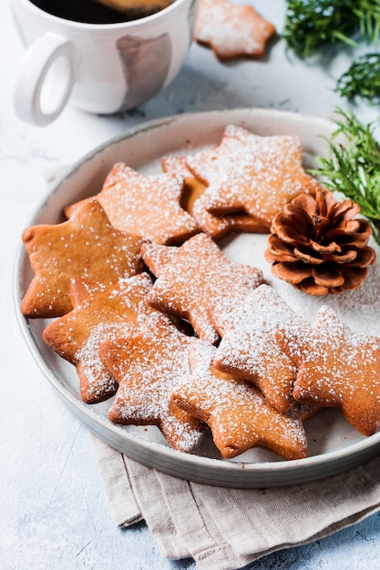 Eigengemaakte de peperkoekkoekjes van de Kerstmisstervorm in ceramische plaat op oude concrete grijze oppervlakte. Bovenaanzicht