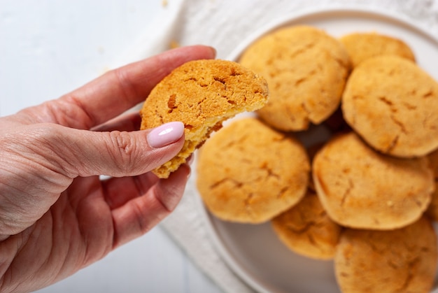 Eigengemaakte gouden bruine graankoekjes op een witte achtergrond met hand die één koekje, hoogste mening houdt