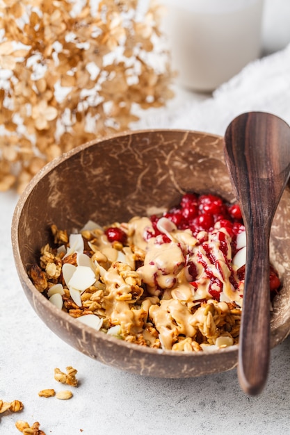 Foto eigengemaakte granola met amerikaanse veenbessen en pindakaas in een kokosnotenkom,.