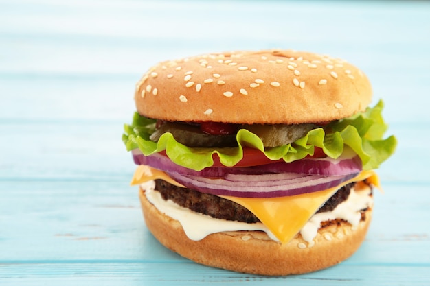 Eigengemaakte hamburger met groenten op blauw.