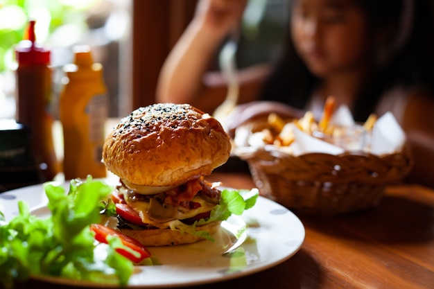 Foto eigengemaakte hamburger met verse groenten op schotel en het frans gebraden in het restaurant