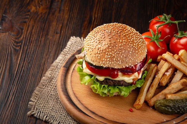 Eigengemaakte hamburgerclose-up met de kaas van de rundvleestomaat sla en franse frietjes op snijplank