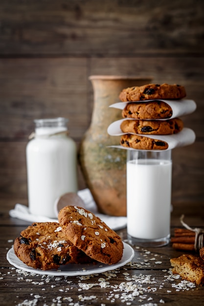 Eigengemaakte havermeelkoekjes met noten en rozijnen en glas melk op donkere houten achtergrond