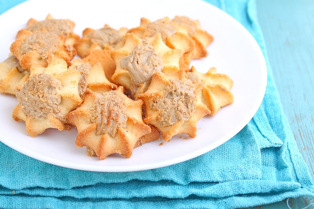 Eigengemaakte koekjes met halva op een witte plaat. Blauwe achtergrond