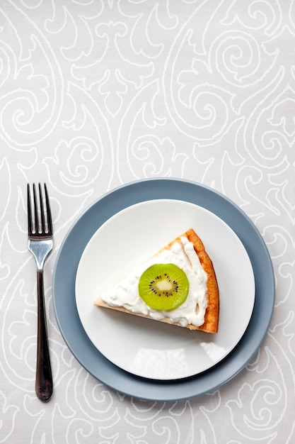 Eigengemaakte kwarkcake met kiwifruit en room op een plaat