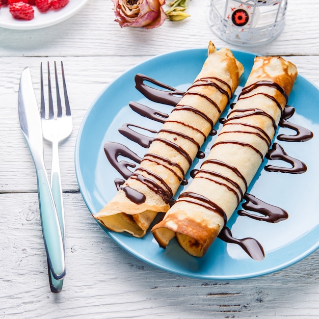 Eigengemaakte pannekoeken of Russische blini met chocoladesaus op plaat