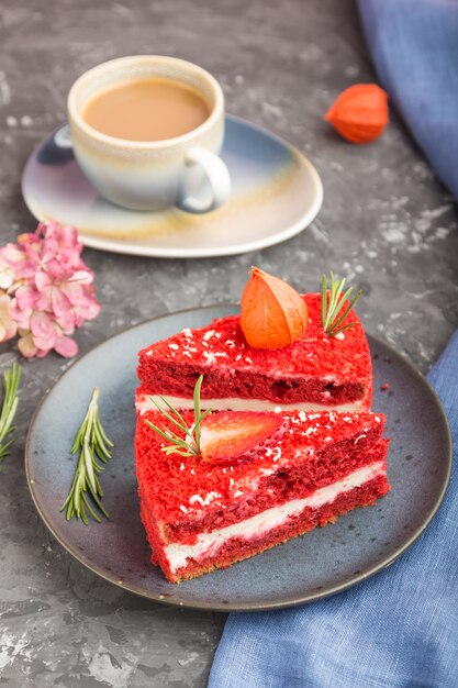 Eigengemaakte rode fluweelcake met melkroom en aardbei met kop van koffie op een zwarte concrete oppervlakte. zijaanzicht, selectieve aandacht.