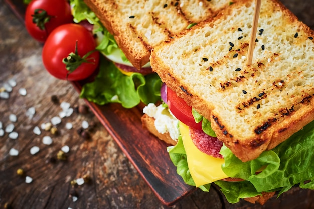 Eigengemaakte sandwich met ham, sla, kaas en tomaat op een houten achtergrond