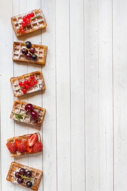 Eigengemaakte wafels met de zomerbessen op een lichte lijst. Selectieve aandacht