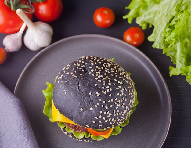 Eigengemaakte zwarte hamburger met kotelet en groenten op de plaat