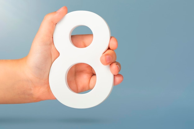 Eight in hand a hand holds a white number on a blue background concept with number eight birthday ye