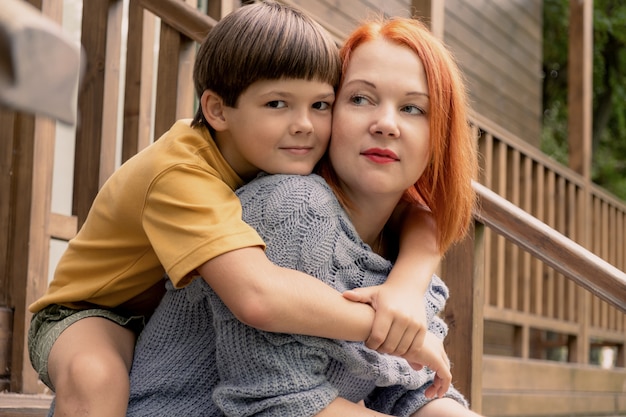 Eightyearold boy hugs his mother by the shoulders