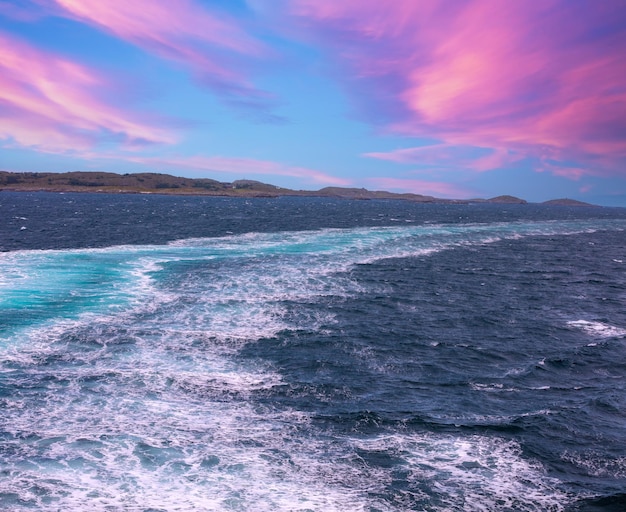 Eiland aan de horizon Rotsen in de zee Prachtig rotsachtig zeelandschap met een dramatische bewolkte lucht Waterpad schuimend achter een veerboot Uitzicht vanaf het schip Natuur van Noorwegen