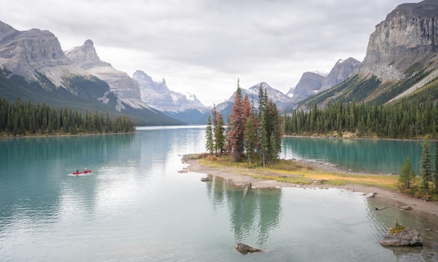 Eiland van bomen in het midden van een turkoois bergmeer omgeven door bergen met kajak Canada