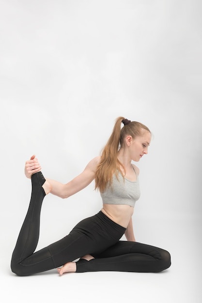 Eka Pada Rajakapotasana. Duif pose. Jonge slanke vrouw beoefent yoga. Gymnastiek opleiding. Oefeningen om flexibiliteit te ontwikkelen.