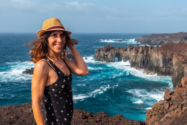 Photo el hierro island canary islands a young tourist woman smiling at the arco de la tosca monument on the coast