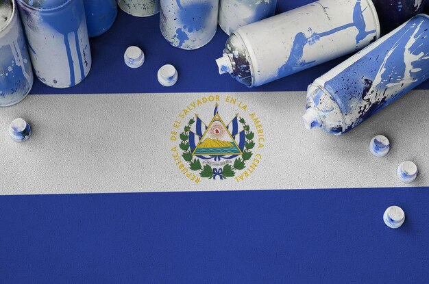 Photo el salvador flag and few used aerosol spray cans for graffiti painting street art culture concept