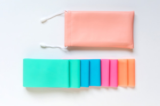 Elastic rubber resistance bands and storage pouch on white background flat lay