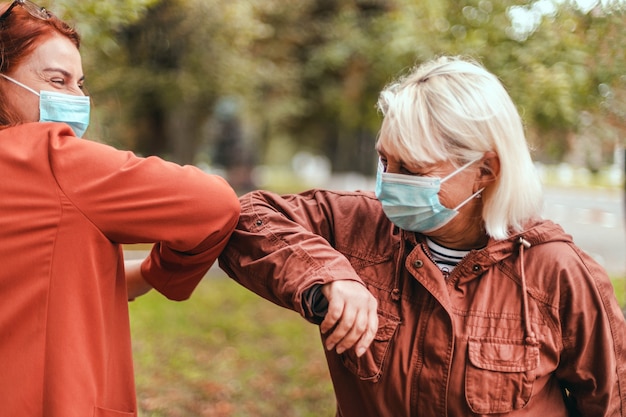 Elbow bump Two people bump elbows to avoid coronavirus outdoors.