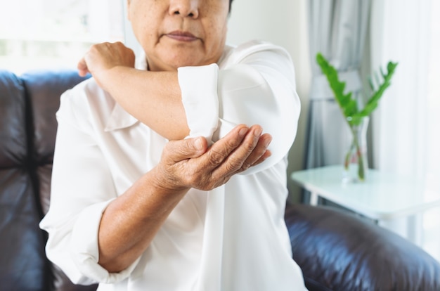 自宅で肘の痛みに苦しんでいる肘の痛み老婆、シニアコンセプトのヘルスケアの問題