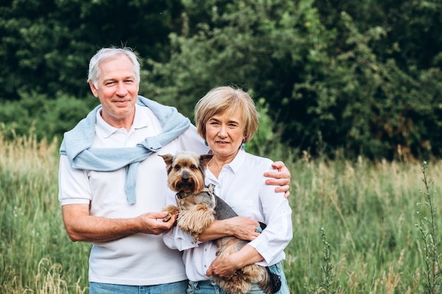 elder couple walks in nature with little dog