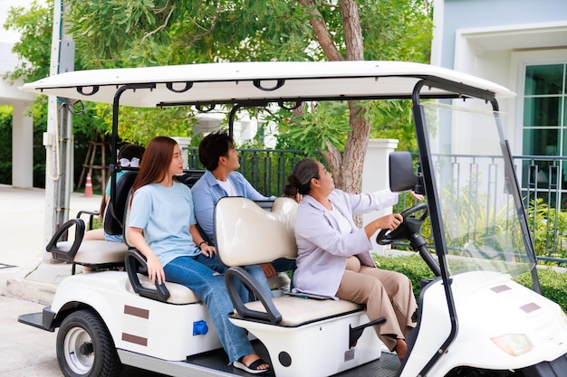 ゴルフカートを運転する高齢者の販売代理店は、不動産を売却するために家族に新しい家を提示します