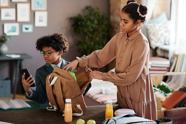 Elder sister helping her brother to pack school bag