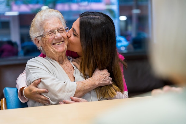 Elder woman and nurse embracing and kissing in a geriatric