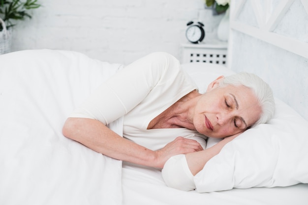 Elder woman sleeping on a white bed 