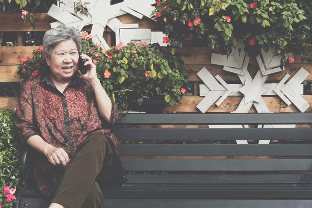 Elder woman talk on mobile phone in garden. 