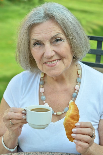 外で朝食とコーヒーを飲みながら年配の女性