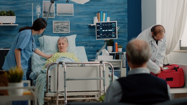 Elder woman with sickness receiving visit from doctor and nurse