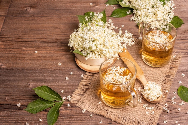 ニワトコの花茶。さわやかな夏の飲み物、健康的なライフスタイルのコンセプト。荒布ナプキン、ヴィンテージの木製テーブル、コピースペース