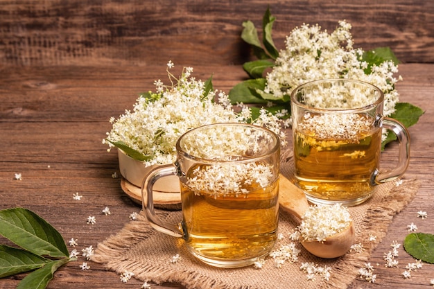 ニワトコの花茶。さわやかな夏の飲み物、健康的なライフスタイルのコンセプト。荒布ナプキン、ヴィンテージの木製テーブル、コピースペース