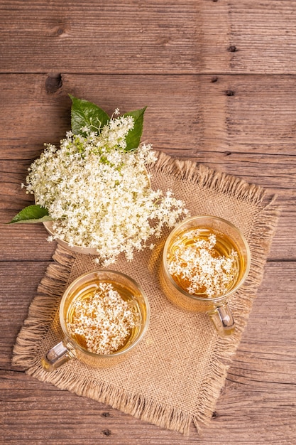 ニワトコの花茶。さわやかな夏の飲み物、健康的なライフスタイルのコンセプト。荒布ナプキン、ヴィンテージの木製テーブル、上面図