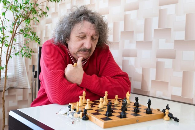 An elderly 60year old man is playing chess