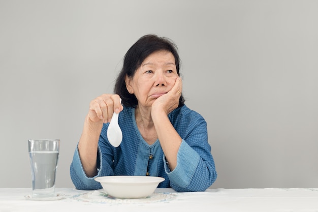 Пожилой азиатской женщине скучно с едой
