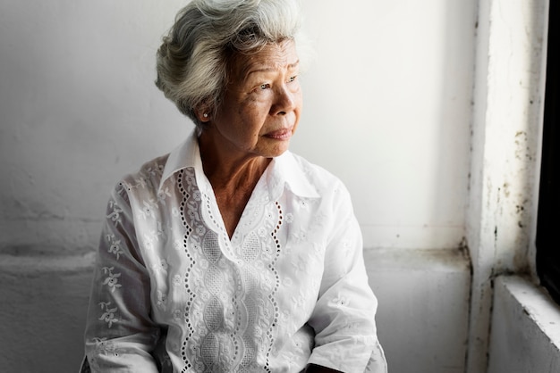 Elderly asian woman looking out of the window