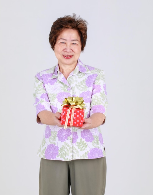 Пожилая тетя, пожилая азиатка, держащая подарочную коробку на белом фоне