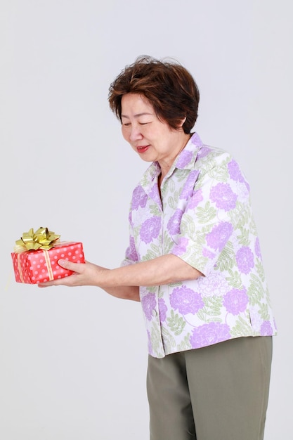 Elderly aunt, Senior Asian woman holding gift box on white background concept